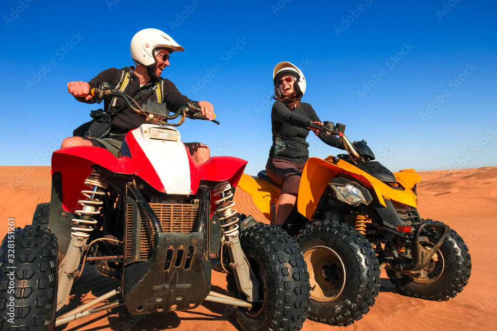 Quad driving people - happy smiling couple bikers in sand desert sunset. Quad driving people - happy smiling couple bikers in sand desert sunset.