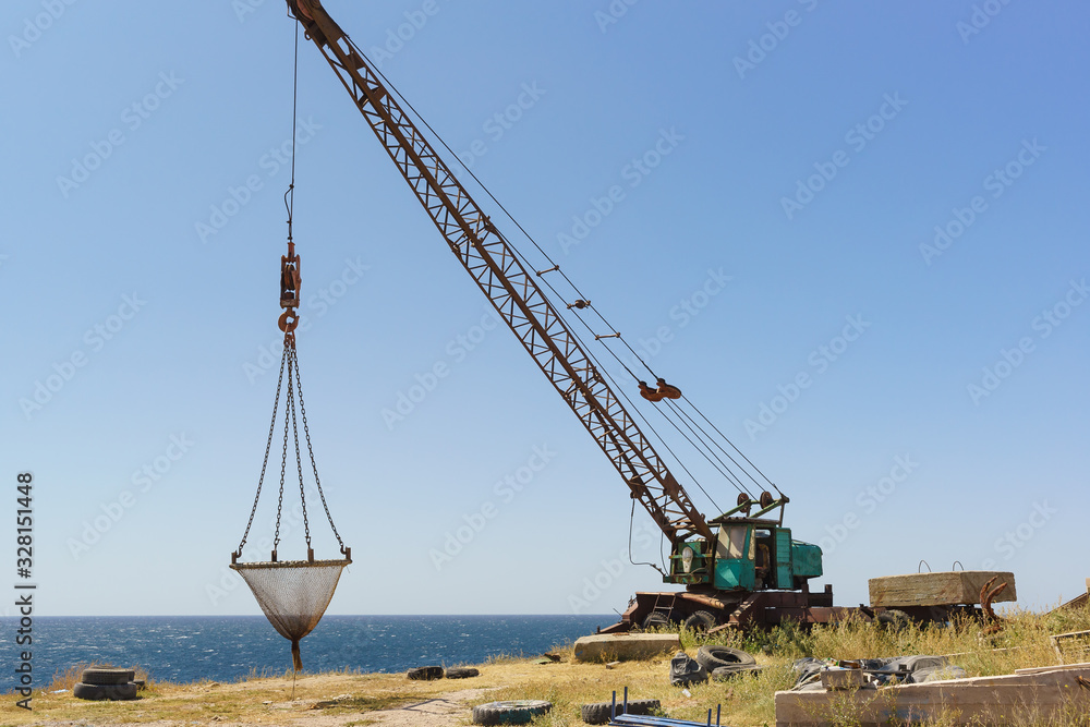 A crane for lifting fishing gear stands on a high, steep beach. Fishing camp on Cape Atlesh. Tarkhankut Peninsula