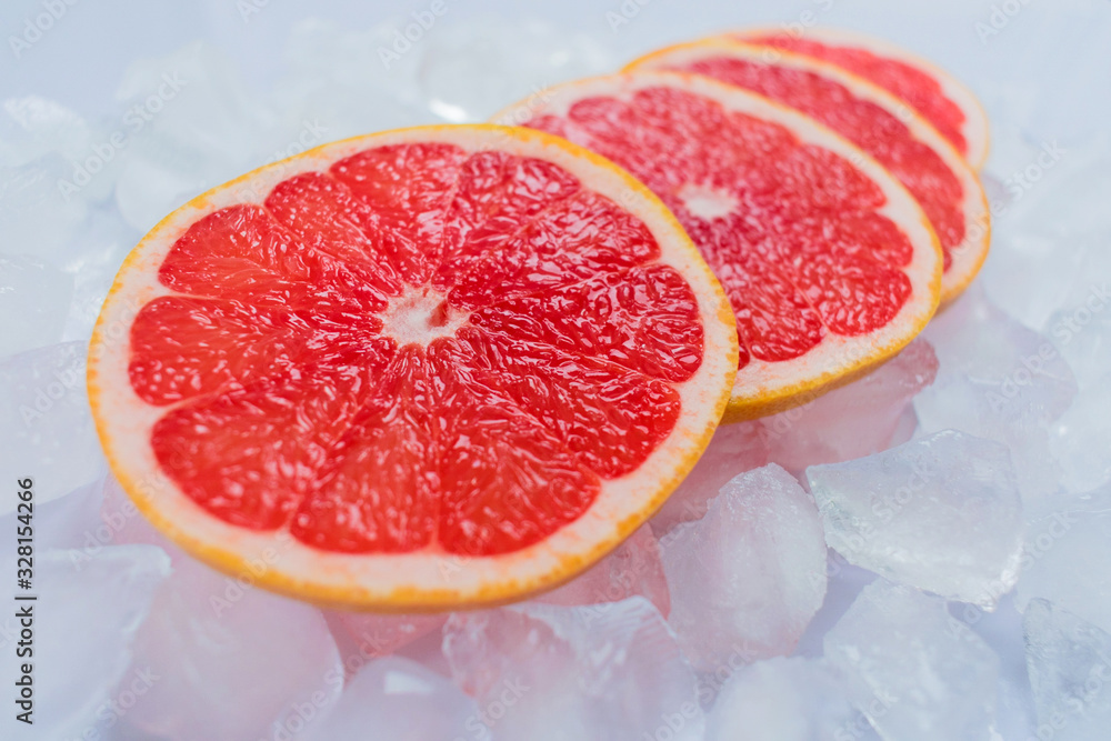 Pieces of grapefruit lie on ice cubes. Close-up. Pieces of grapefruit lie on ice cubes. Close-up.