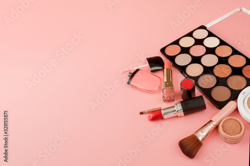 Various makeup productson pink background with copyspace