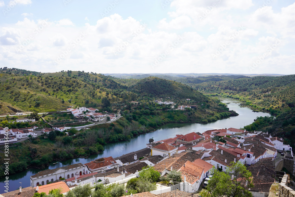 Small town of Mertola in Portugal seen from above, roofs of the houses and river. 