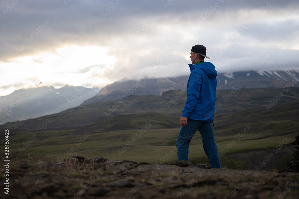 Backside of tall caucasian man wearing jacket standing in over snowy mountain on the Laugavegur track, Iceland. Promoting healthy lifestyle
