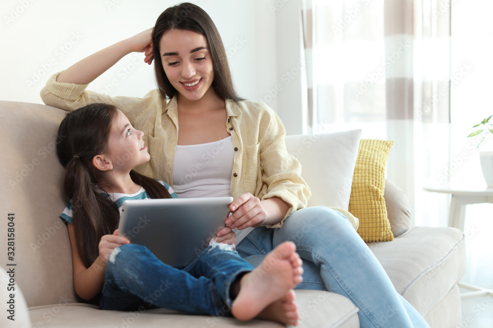 Mother and daughter reading E-book together at home Mother and daughter reading E-book together at home