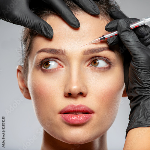 Caucasian woman getting botox cosmetic injection in forehead. Woman gets botox injection in her face