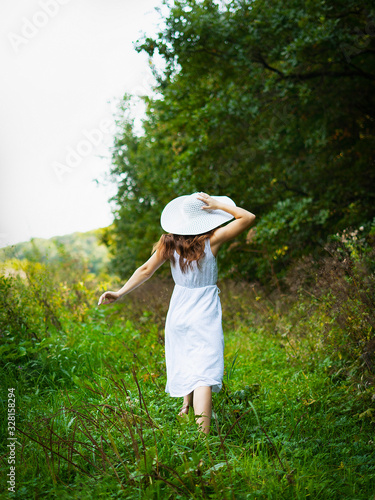 A woman in a dress. Woman in the park. A woman walks in the park in a white dress © chdenisz