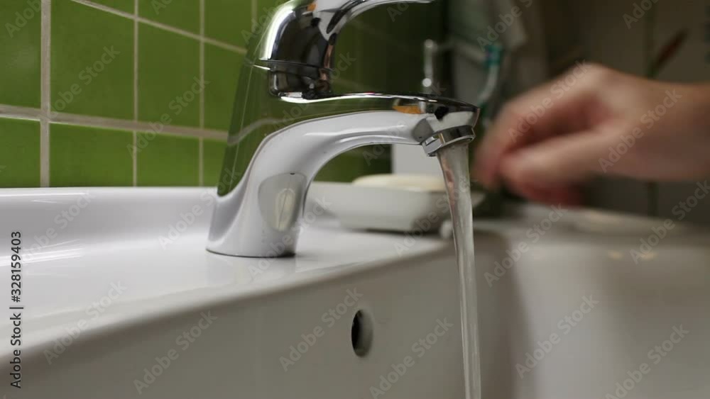 man washes his hands in the washstand under the stream of water man washes his hands in the washstand under the stream of water