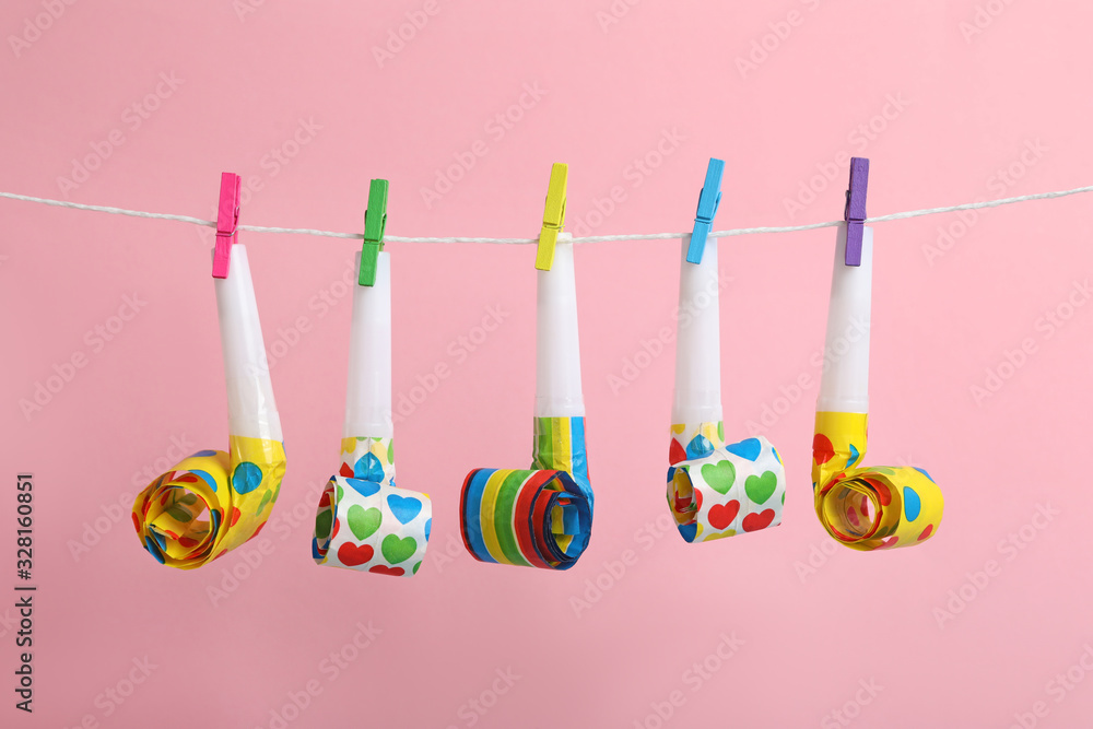Party horns with pegs on laundry line against pink background. April Fool's Day Party horns with pegs on laundry line against pink background. April Fool's Day
