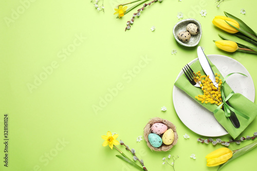 Canvas Print Festive Easter table setting with eggs and floral decor on green background, flat lay