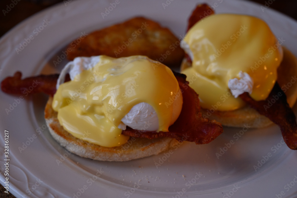Weekend brunch in Scotland with two eggs benedict on homemade muffuns with roasted bacon and yellow hollandaise sauce. Weekend brunch in Scotland with two eggs benedict on homemade muffuns with roasted bacon and yellow hollandaise sauce.