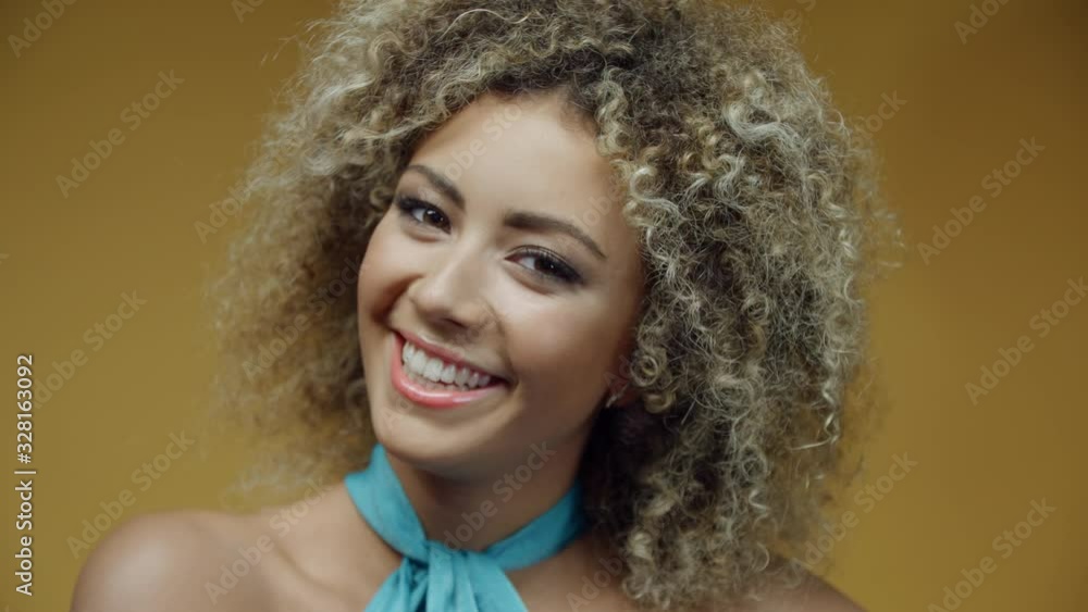 Close-up portrait of young happy hispanic woman in turquoise dress on yellow background at summer party. Cheerful mixed race girl is laughing and looking at camera Close-up portrait of young happy hispanic woman in turquoise dress on yellow background at summer party. Cheerful mixed race girl is laughing and looking at camera