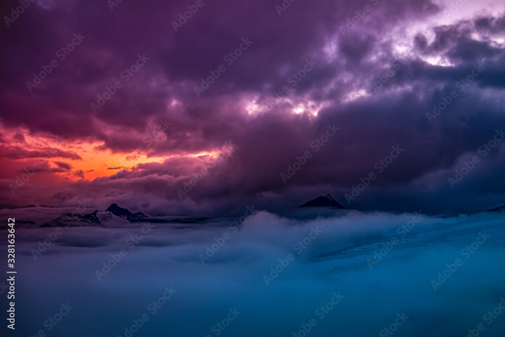 Panorama of high mountains and clouds, colorful sunset in the background. Mount Elbrus, Caucasus, Russia.