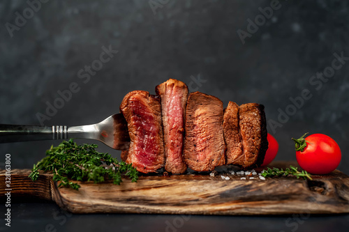 four steaks on  fork on a cutting board on a stone background.Four types of meat frying Rare, Medium, Medium Well, Well Done photo