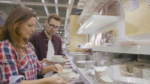 Young couple choosing plates in houseware store
