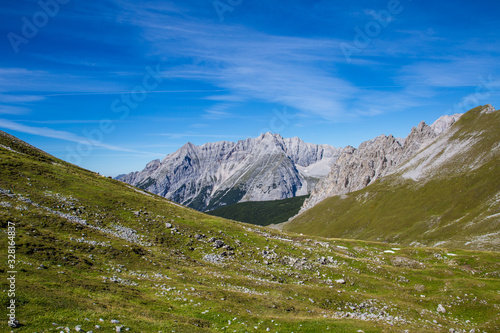 Hiking trail to the Hafelekar with a view on the J  gerkarspitze mountain in tyrol  austria. Mountains are beatifully enframed by grassland with blue sky.