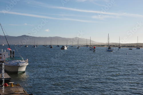 Tranquil winter day scene at Morro Bay with boats and mountains and blu sky shortly before sunset