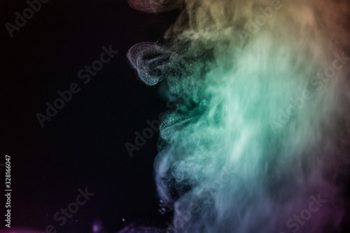 Colorful smoke flowing in a dark background. Abstract backdrop with fume and colorful light effect. Mystic dream. Colorful dust explode. Paint Holi. Halftone smoke effect. Vibrant abstract background.