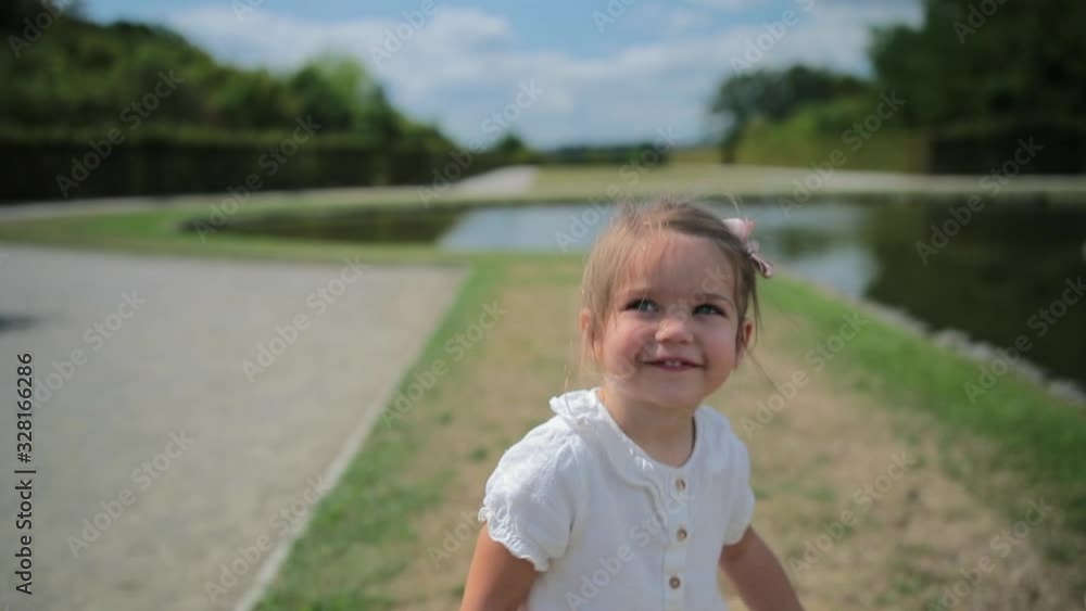 Slow motion close up of young girl smiling and waving outdoors in park Slow motion close up of young girl smiling and waving outdoors in park