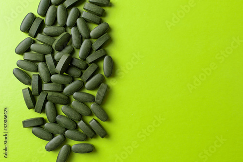 green pills chlorella on a green background. nutritional supplements for a healthy diet