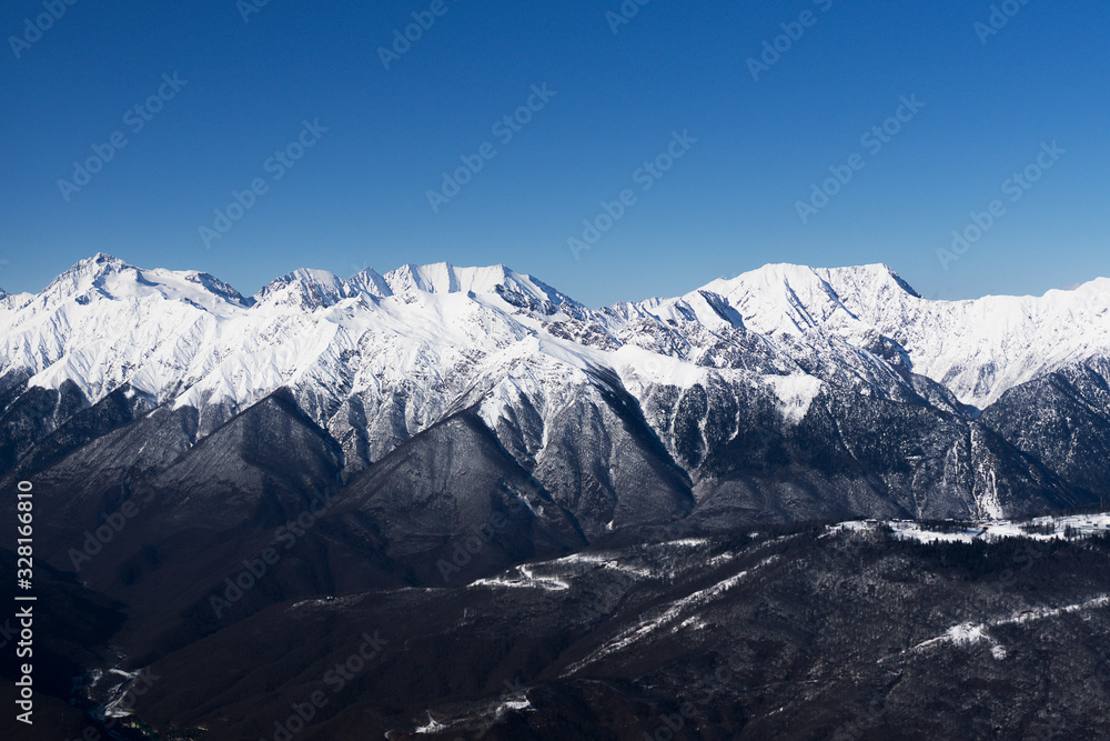 A mountain range covered with snow against a blue sky Caucasus mountains