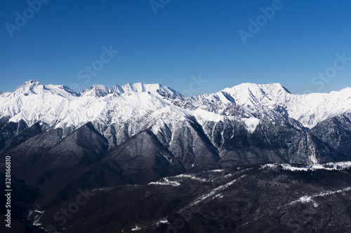 A mountain range covered with snow against a blue sky Caucasus mountains