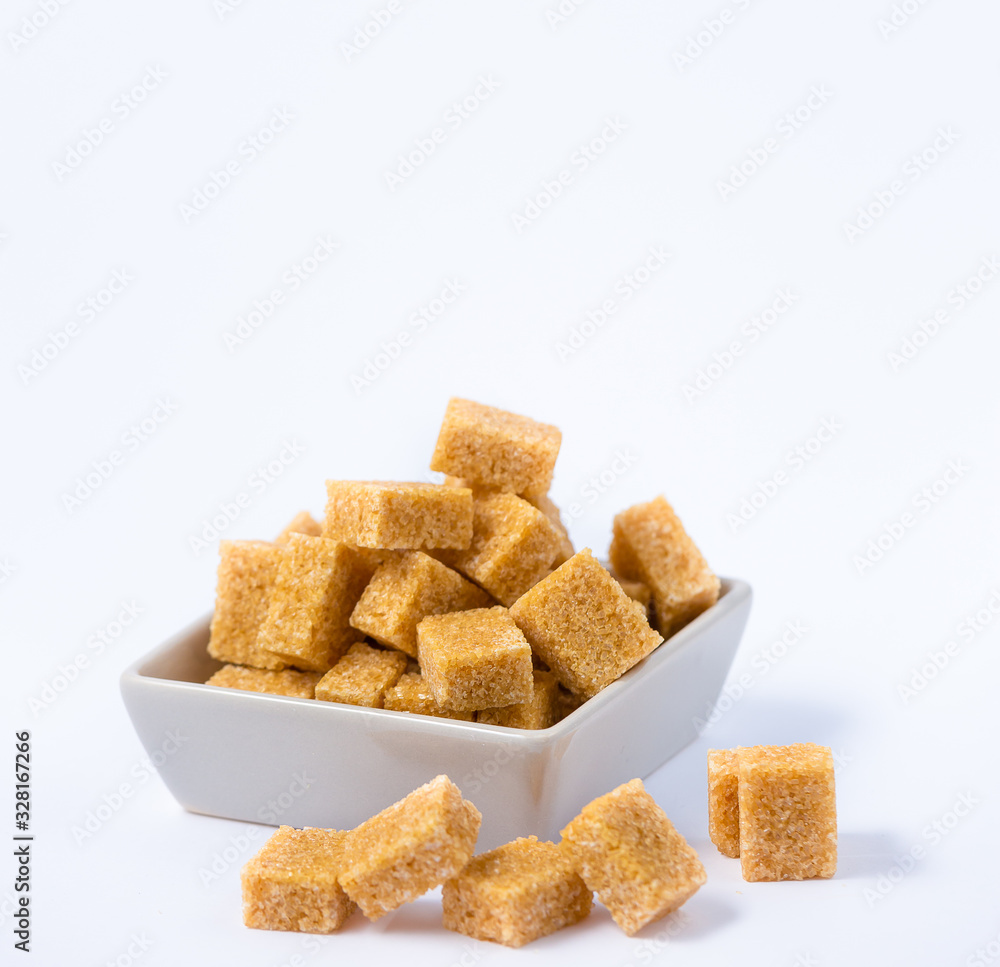 Brown sugar in a square cup on a white background, healthy sugar is used for cooking or desserts. Brown sugar in a square cup on a white background, healthy sugar is used for cooking or desserts.
