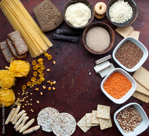  gluten free set. Gluten free food. Various gluten free pasta, bread, snacks and flour, top view. Grains of corn. Brown background with drops of paint.Square composition. Place for text.