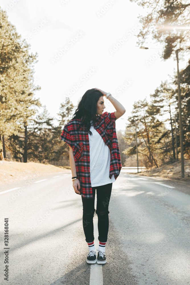 Awesome girl in trendy clothes standing on the road at the forest. Beautiful look, spring. Soft colours. Awesome girl in trendy clothes standing on the road at the forest. Beautiful look, spring. Soft colours.