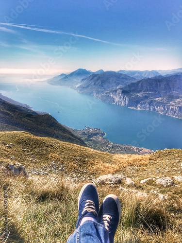 legs in gym shoes on top of a mountain near Lake Garda in Italy