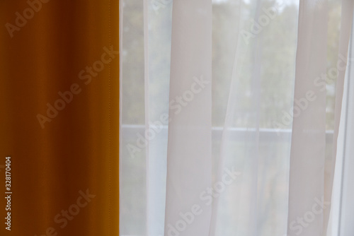 Window curtains, light tulle and a dark curtain from the sun. the window is half closed