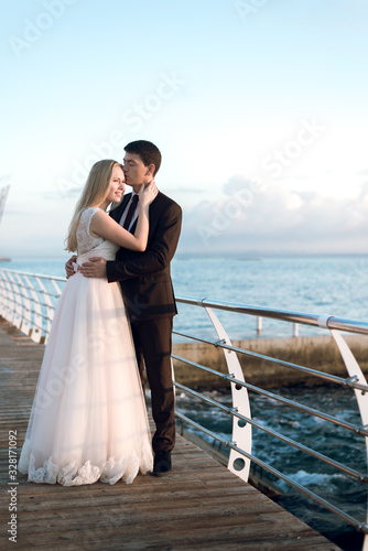 portrait of the bride and groom,newlyweds on the background of the sea,happy wedding couple on sea beach,newlyweds are hugging on the wedding day after the ceremony,wedding dresses on the bride  © Vadym