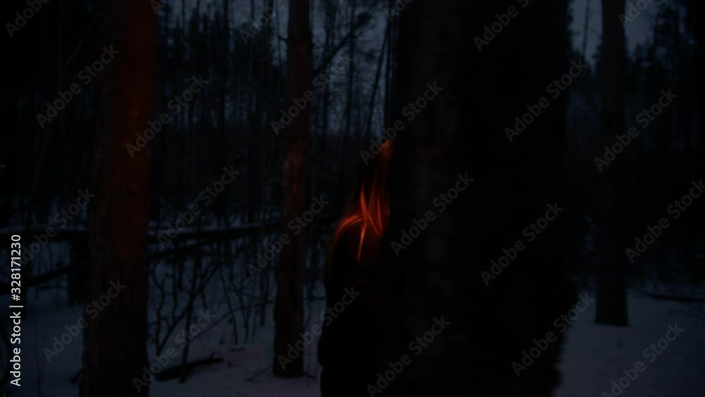 Young lost and scared woman with a fire torch walking in the night forest searching for the way out Young lost and scared woman with a fire torch walking in the night forest searching for the way out