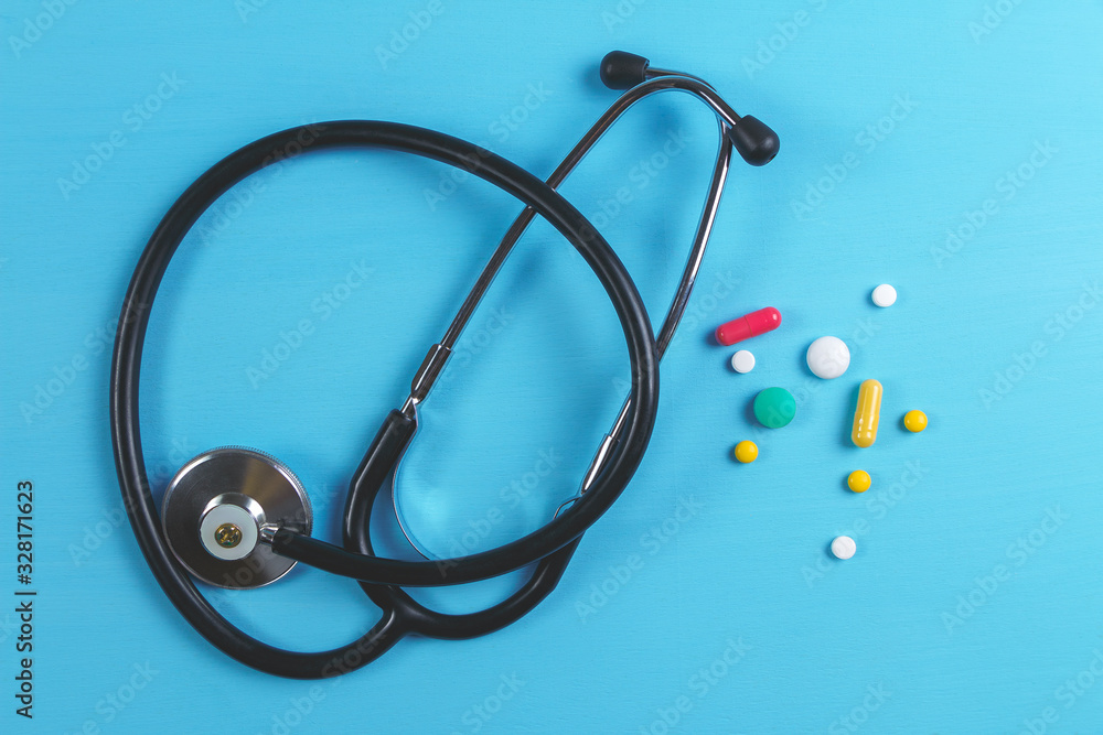 Stethoscope and multicolored tablets and capsules on a blue background Stethoscope and multicolored tablets and capsules on a blue background
