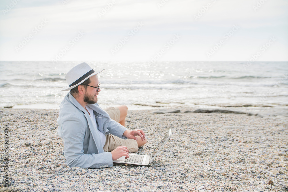 man freelancer working remotely on the beach of the sea