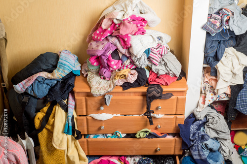 Fotografie open chest drawers with drop-down clothes and piles of clothes around in a mess
