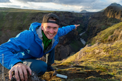 Caucasian young guy standing in over mountain and canyon background on the way of Laugavegur trail, Iceland. Promoting healthy lifestyle