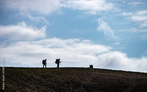 Silhouettes of people walking with backpacks on the sky background