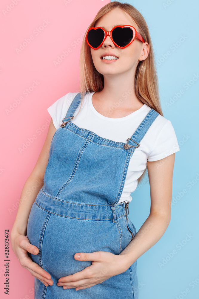 Fototapeta premium happy young pregnant woman in heart-shaped sunglasses