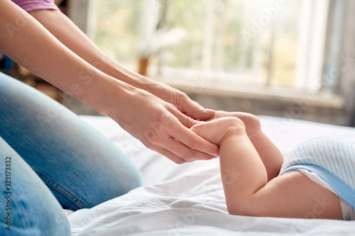 Young adult mother making massage to her little new born baby