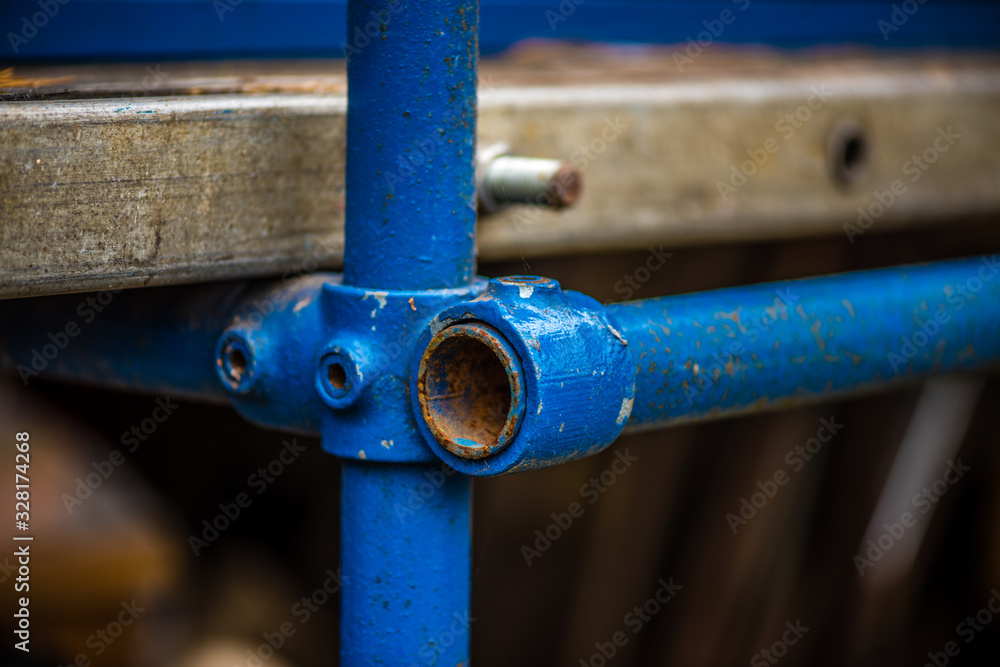 rusty scaffolding pipe junction in blue