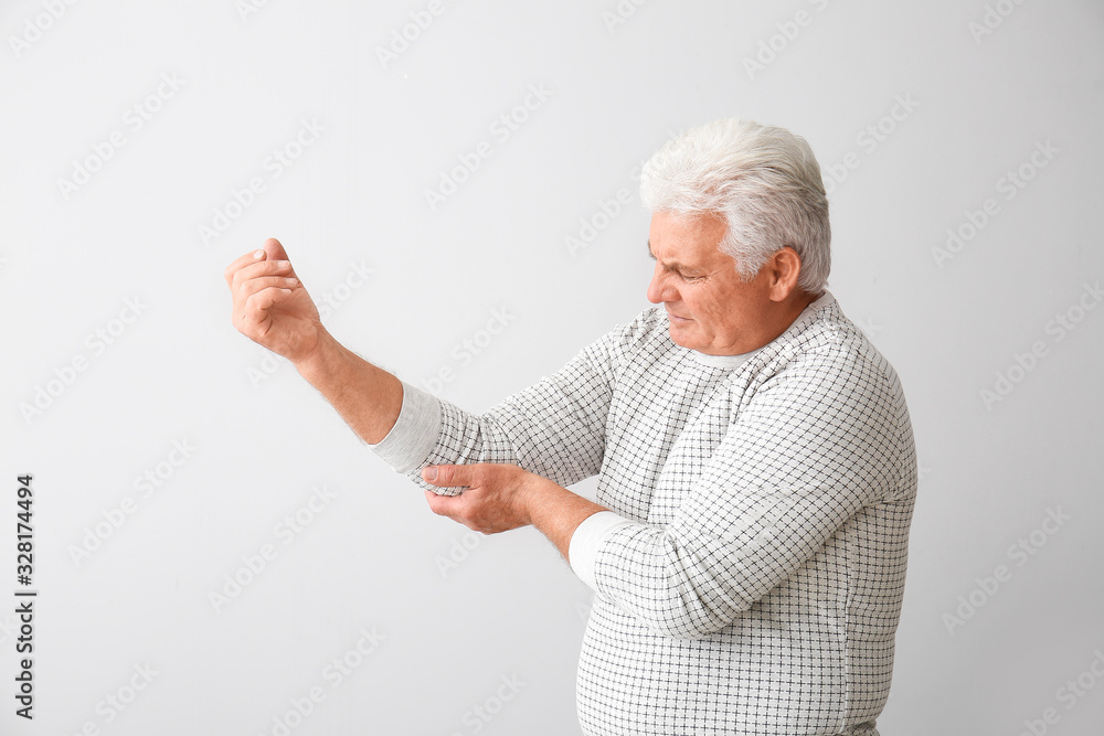 Senior man suffering from Parkinson syndrome on grey background Senior man suffering from Parkinson syndrome on grey background