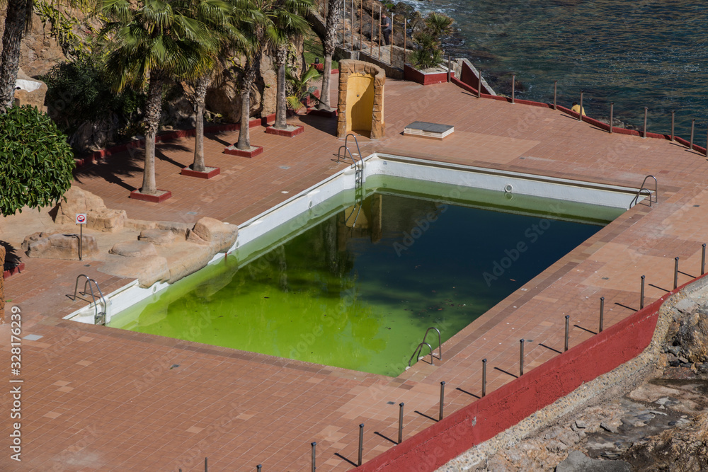 a dirty and abandoned pool with green water, scary pool, dyrty waterl, abandoned swimming pool, ruined pool