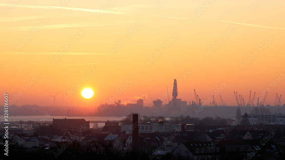 Sonnenaufgang am Hafen von Rostock von Warnemünde aus gesehen