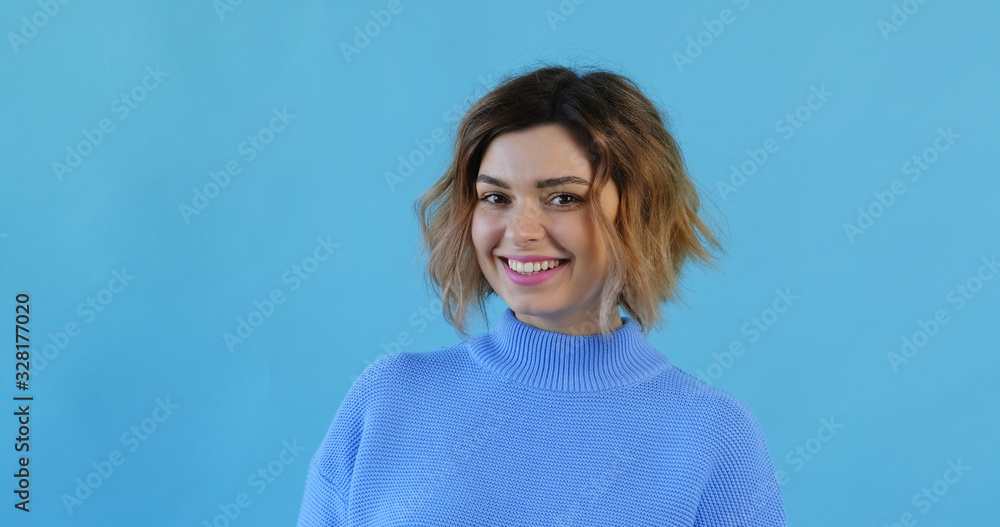 Portrait of happy smiling young sexy girl blue sweater and stands on blue background. Pleasure. Emotions of people. Monotone. Copy space. Blue pantone Portrait of happy smiling young sexy girl blue sweater and stands on blue background. Pleasure. Emotions of people. Monotone. Copy space. Blue pantone