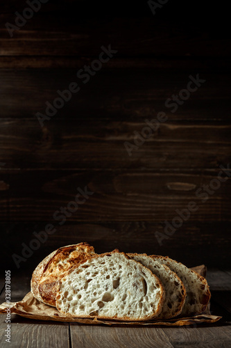 Fototapeta Bread, traditional sourdough bread cut into slices on a rustic wooden background