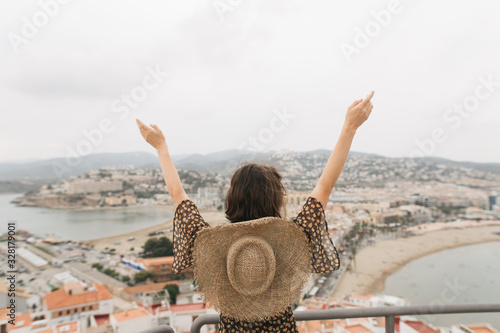 young female traveler stands on top of castle, city view, Peniscola Spain photo