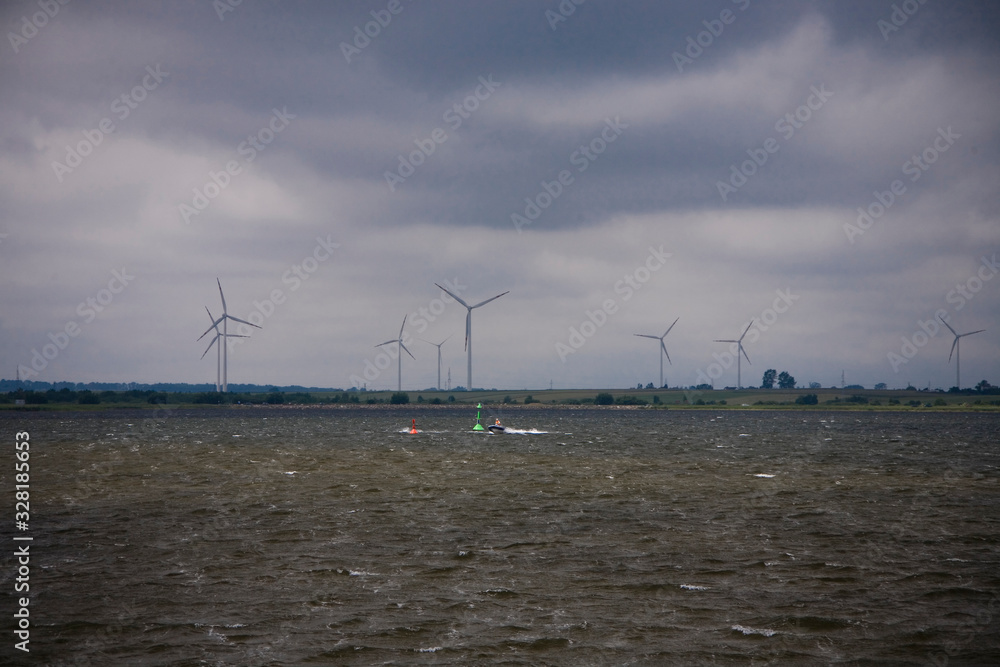  summer landscape with a cloudy sky and a wind farm on the horizon at Puck Bay in Poland