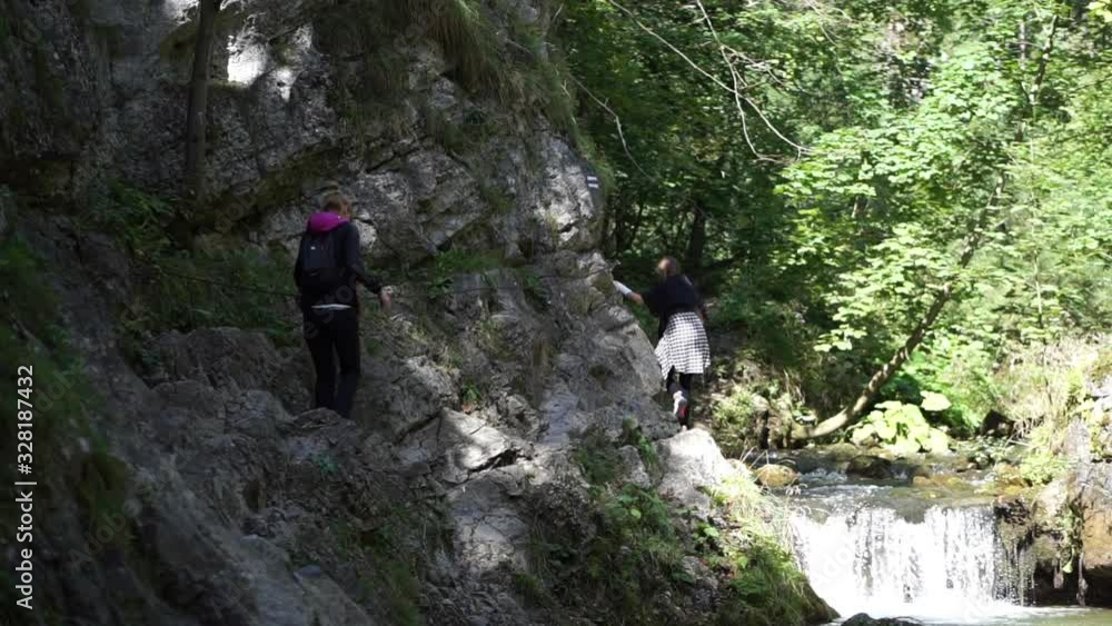 Two Young Ladies Climbing Up A Steep Rocky Mountain On A Sunny Day - Wide Shot Two Young Ladies Climbing Up A Steep Rocky Mountain On A Sunny Day - Wide Shot