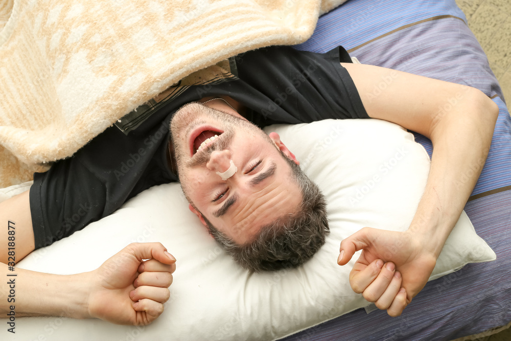 Man awakening after using a nasal strip. External nasal dilator strip