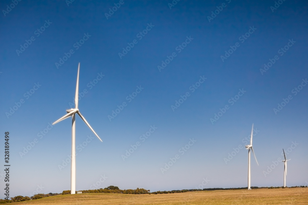 Three tall wind turbines under blue sky with copy space - clean energy concept Three tall wind turbines under blue sky with copy space - clean energy concept