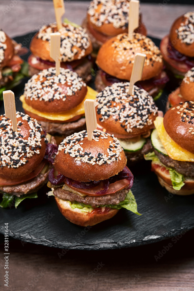 Set of homemade delicious hamburgers made of beef, bacon, cheese, salad and tomatoes on a dark concrete background. Fat junk food close up. With copy space. Fast food pattern Set of homemade delicious hamburgers made of beef, bacon, cheese, salad and tomatoes on a dark concrete background. Fat junk food close up. With copy space. Fast food pattern